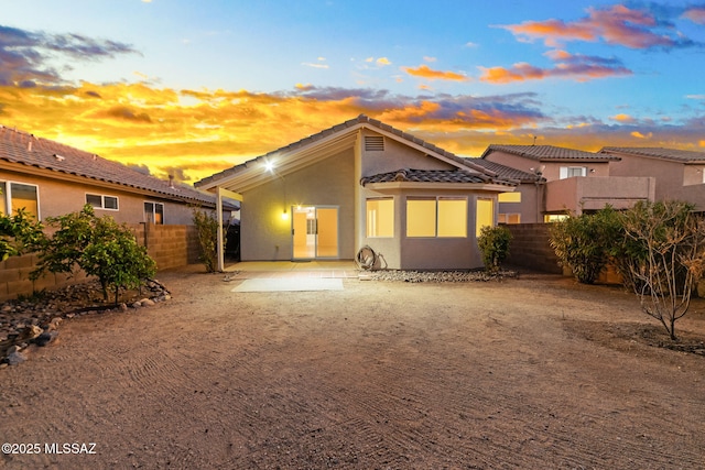 back of property at dusk with a patio area, a fenced backyard, and stucco siding
