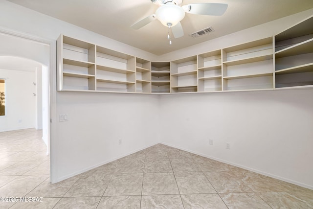spare room featuring ceiling fan, visible vents, arched walkways, and tile patterned floors