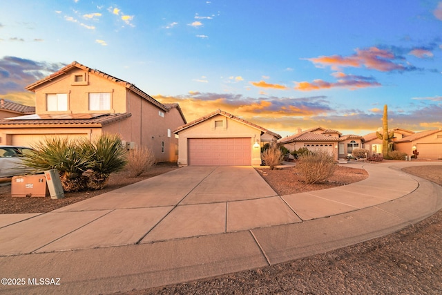mediterranean / spanish-style home with a garage, driveway, a tiled roof, and stucco siding