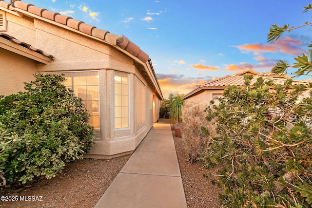 view of side of property featuring a tile roof and stucco siding