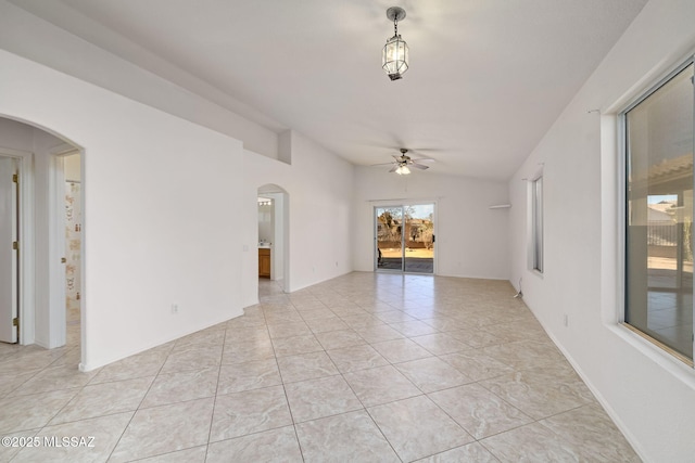 spare room featuring arched walkways, light tile patterned floors, lofted ceiling, and a ceiling fan