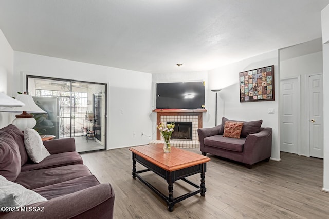 living area featuring baseboards, wood finished floors, and a tile fireplace