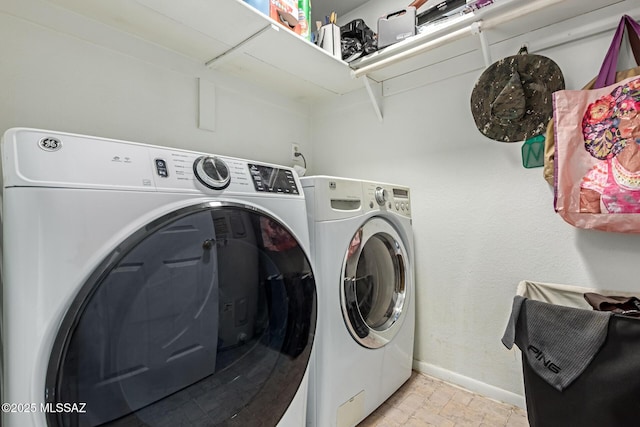 washroom featuring laundry area, separate washer and dryer, stone finish floor, and baseboards