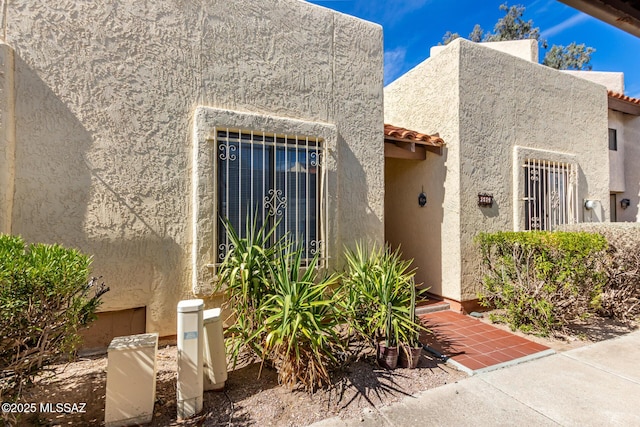 entrance to property with a tiled roof and stucco siding