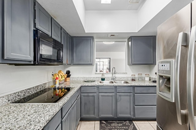 kitchen with gray cabinets, visible vents, light tile patterned flooring, a sink, and black appliances