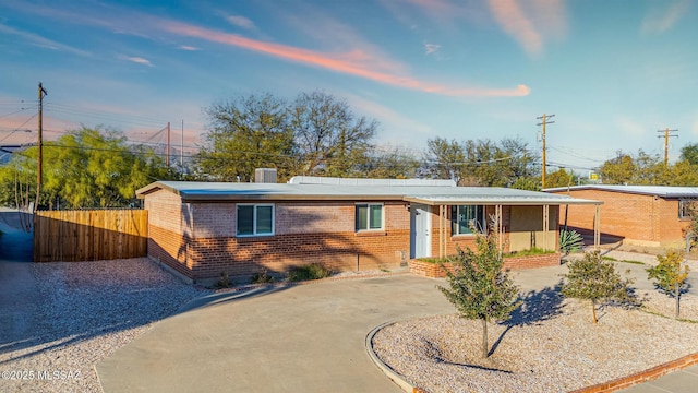 view of front of house with driveway, fence, and brick siding