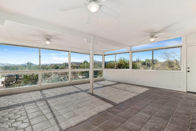 unfurnished sunroom featuring a mountain view and a ceiling fan