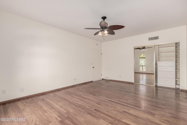 spare room with a ceiling fan, baseboards, visible vents, and wood finished floors