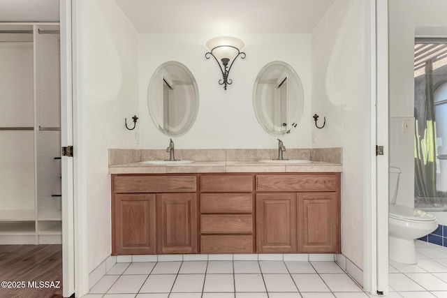 bathroom with tile patterned floors, a sink, toilet, and double vanity