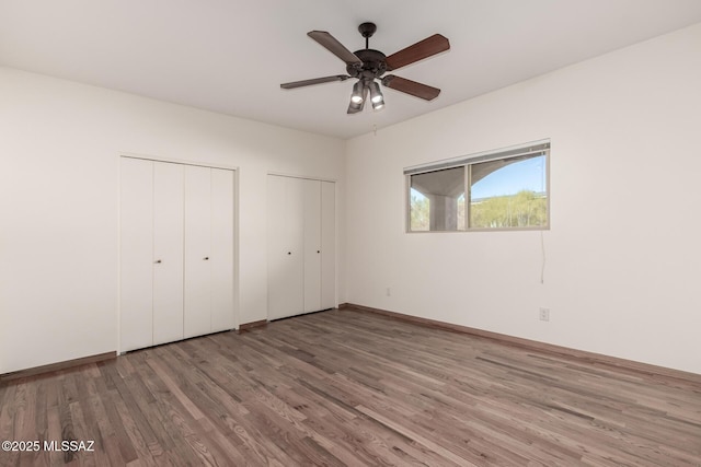 unfurnished bedroom featuring two closets and wood finished floors