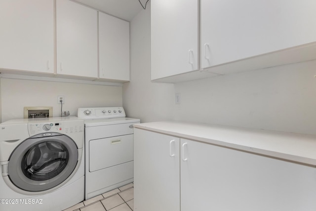 washroom with cabinet space, washing machine and dryer, and light tile patterned flooring