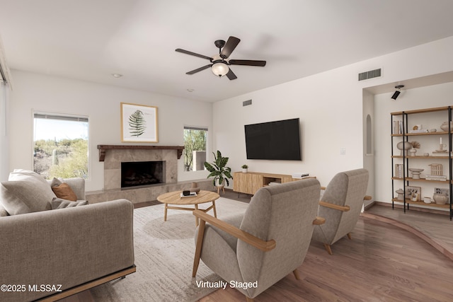 living room featuring visible vents, arched walkways, a ceiling fan, wood finished floors, and a high end fireplace