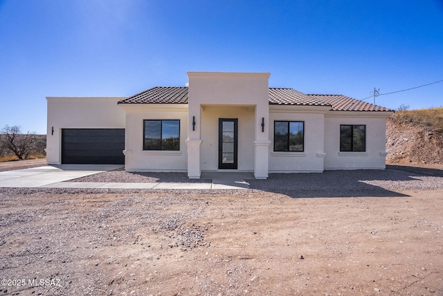 view of front facade featuring an attached garage, driveway, a tile roof, and stucco siding