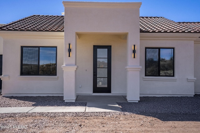 mediterranean / spanish house featuring a tile roof and stucco siding