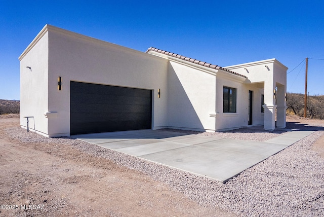 view of front of home with a garage, concrete driveway, a tiled roof, and stucco siding