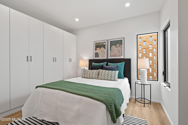 bedroom featuring light wood-style flooring, baseboards, a closet, and recessed lighting