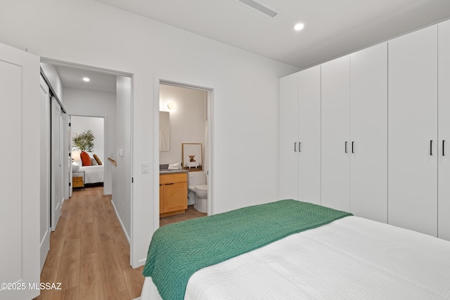 bedroom featuring light wood finished floors, visible vents, ensuite bathroom, and recessed lighting