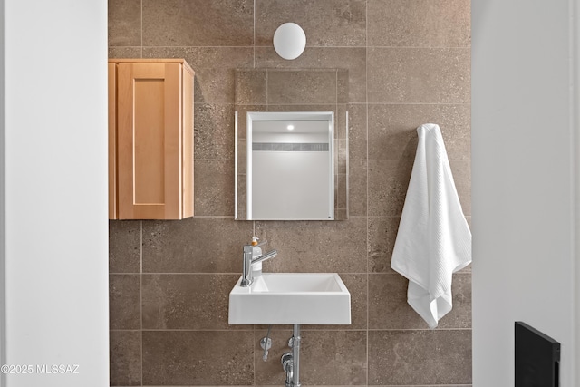 bathroom featuring a sink and tile walls