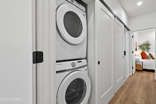 laundry room featuring stacked washer and dryer, light wood-style flooring, laundry area, and recessed lighting