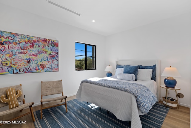 bedroom featuring baseboards, wood finished floors, and recessed lighting