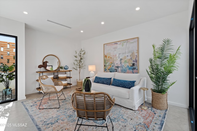 living area with finished concrete flooring, visible vents, baseboards, and recessed lighting