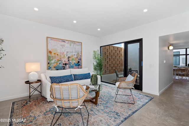 living room with concrete flooring, recessed lighting, and baseboards