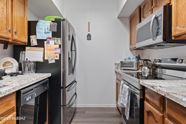 kitchen with stainless steel appliances, brown cabinets, dark wood-type flooring, and light stone countertops