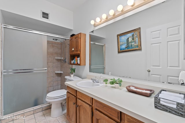 bathroom featuring a shower with door, visible vents, toilet, vanity, and tile patterned floors