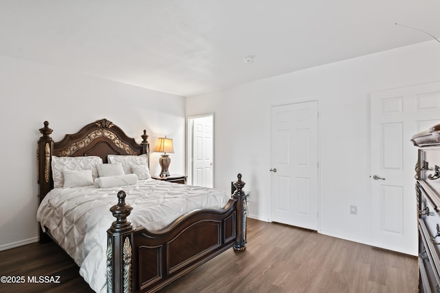 bedroom featuring baseboards and dark wood-type flooring