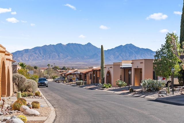 view of road with street lights, sidewalks, a mountain view, curbs, and a residential view