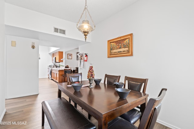 dining space featuring light wood-style floors, baseboards, and visible vents