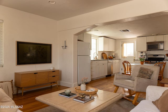living area with visible vents, baseboards, and wood finished floors