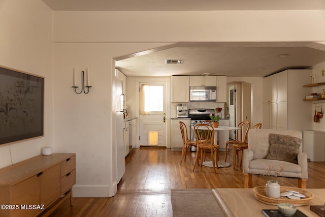 living room with light wood-style floors, visible vents, and baseboards