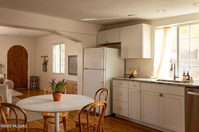 kitchen featuring wood finished floors, white cabinetry, freestanding refrigerator, a sink, and dishwasher