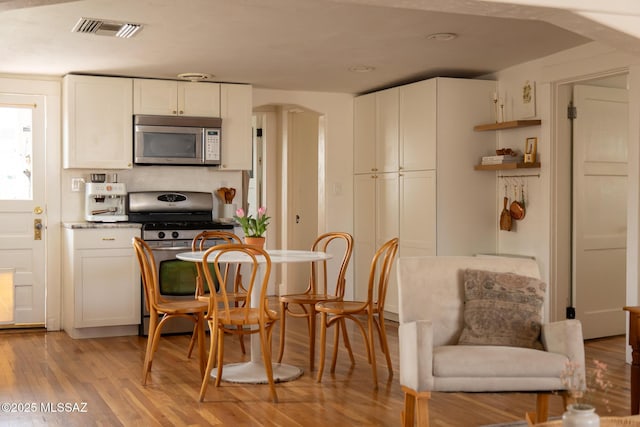 kitchen featuring white cabinets, light wood-style floors, visible vents, and stainless steel appliances