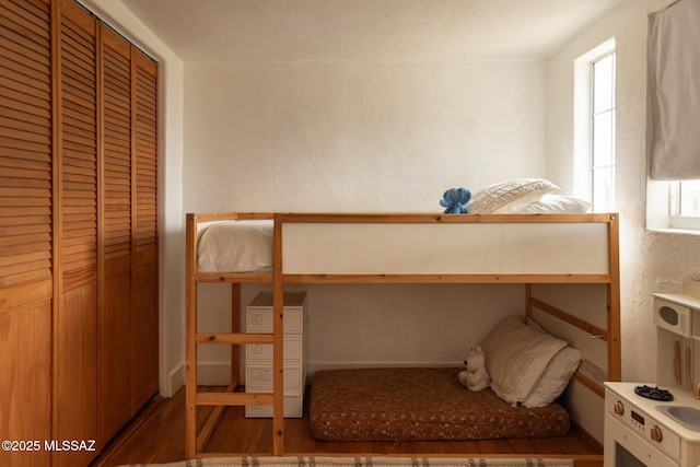 unfurnished bedroom featuring multiple windows, wood finished floors, and a textured wall