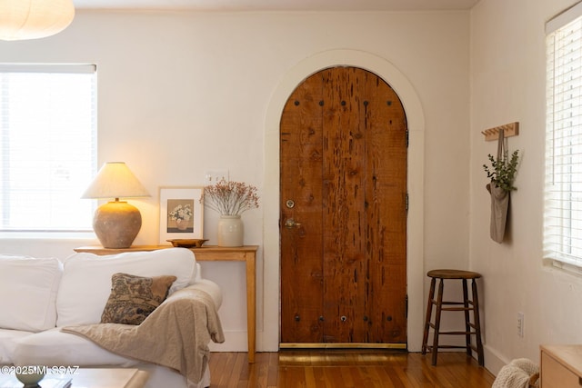 interior space with wood finished floors, arched walkways, and baseboards