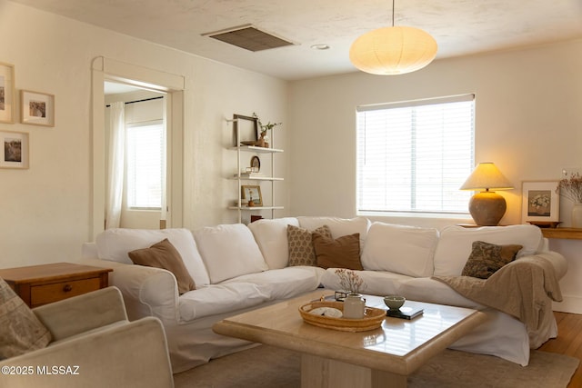 living area with visible vents and wood finished floors