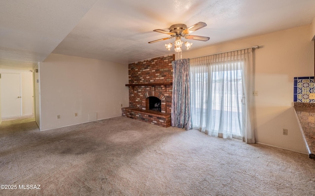 unfurnished living room with carpet floors, a brick fireplace, ceiling fan, and a textured ceiling