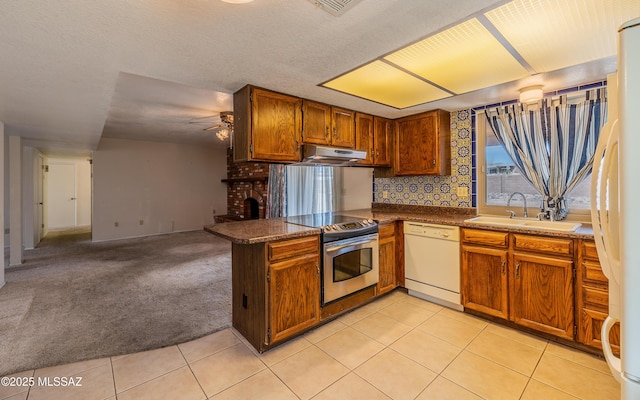 kitchen featuring under cabinet range hood, light carpet, a peninsula, white appliances, and a sink