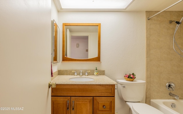 bathroom featuring toilet, shower / bathtub combination, a textured wall, and vanity