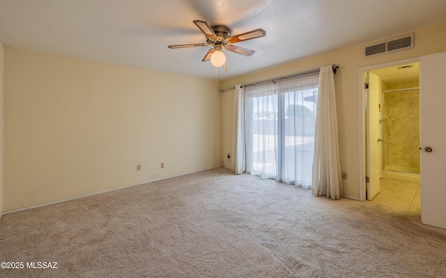 carpeted empty room featuring ceiling fan and visible vents