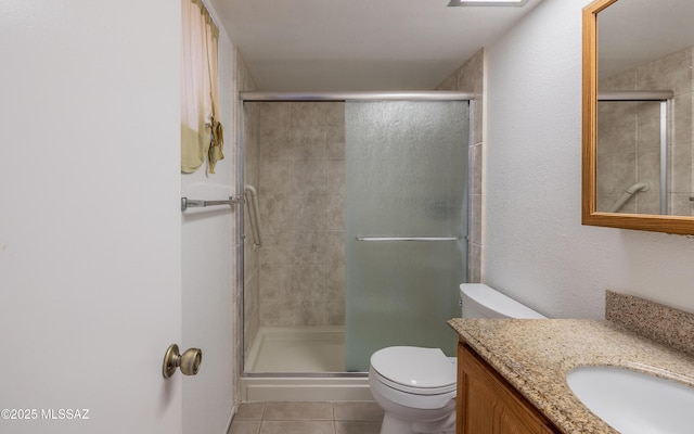 full bath featuring a stall shower, tile patterned flooring, vanity, and toilet