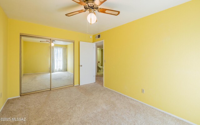 unfurnished bedroom with carpet floors, a ceiling fan, visible vents, and a closet