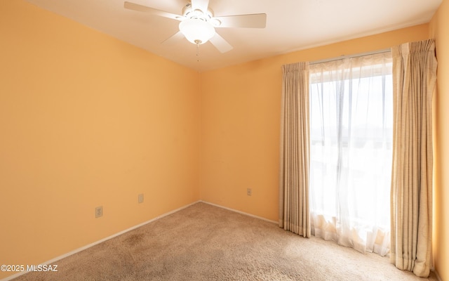 carpeted empty room with ceiling fan and baseboards