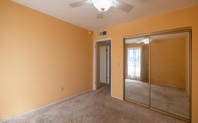 unfurnished bedroom featuring carpet floors, a closet, visible vents, and ceiling fan