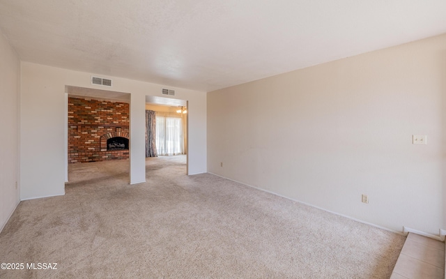 carpeted spare room with visible vents and a fireplace