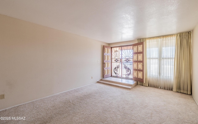 spare room featuring a textured ceiling and light colored carpet