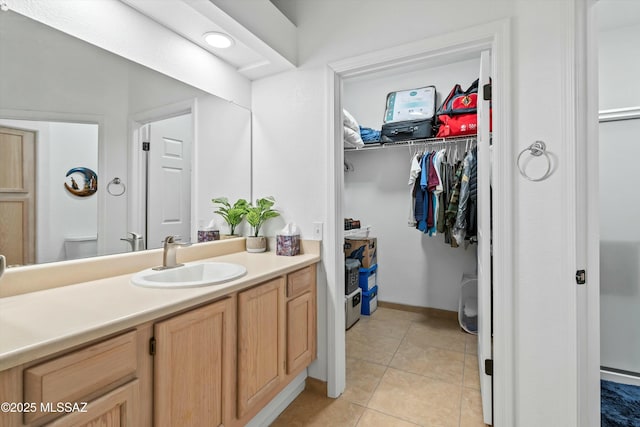 bathroom featuring tile patterned flooring, vanity, baseboards, and a spacious closet