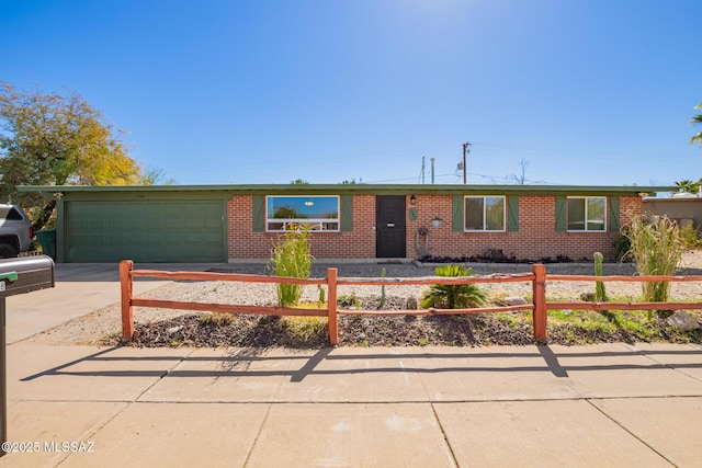 ranch-style house featuring a fenced front yard, brick siding, driveway, and an attached garage